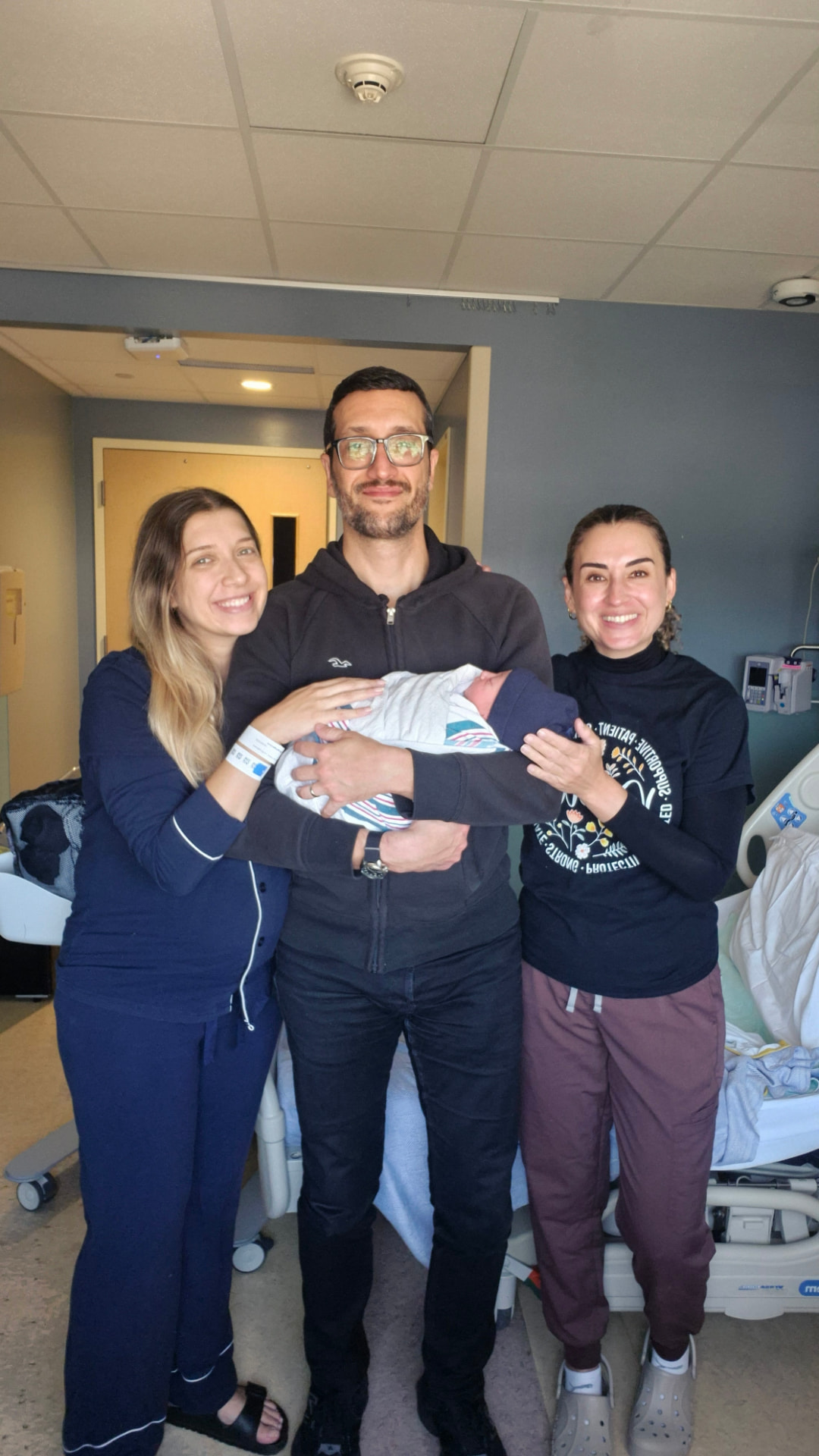 A doula standing with new parents as they hold their newborn