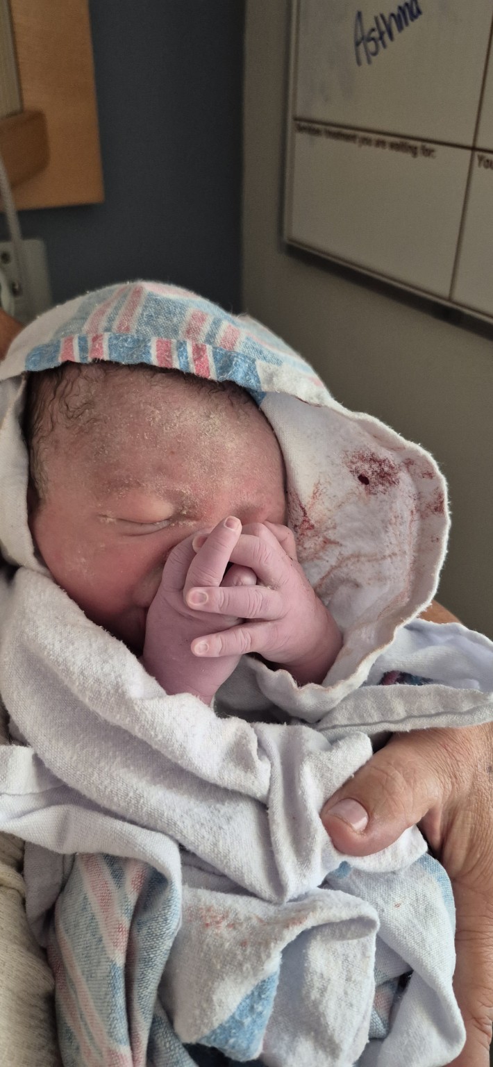 A newborn resting with hands tucked close to their face
