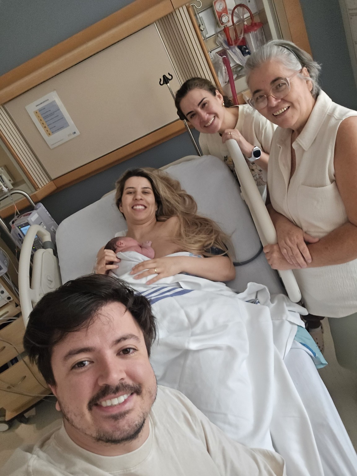 A family gathered around a parent and newborn in hospital